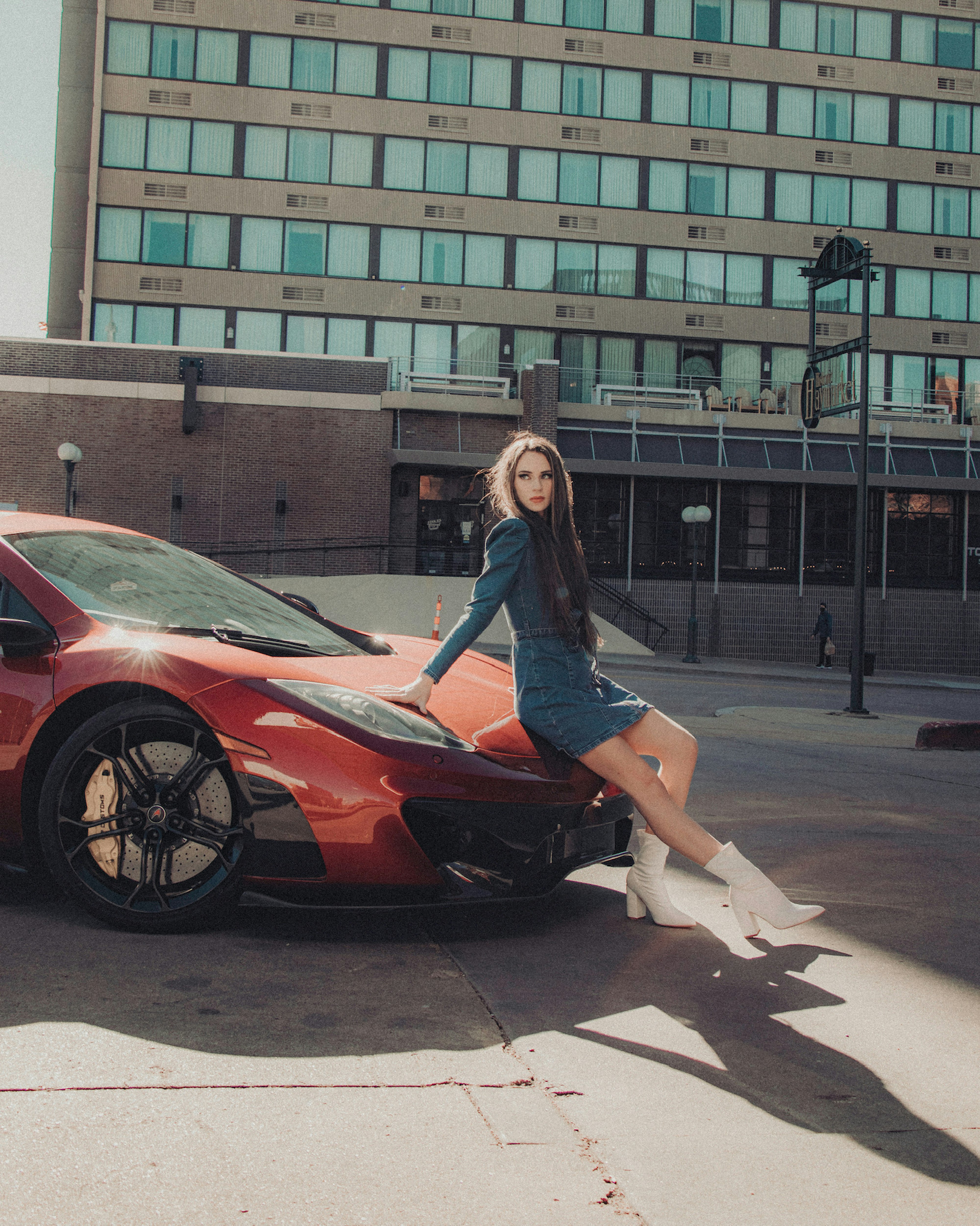 woman in blue long sleeve shirt and black skirt standing beside red car during daytime